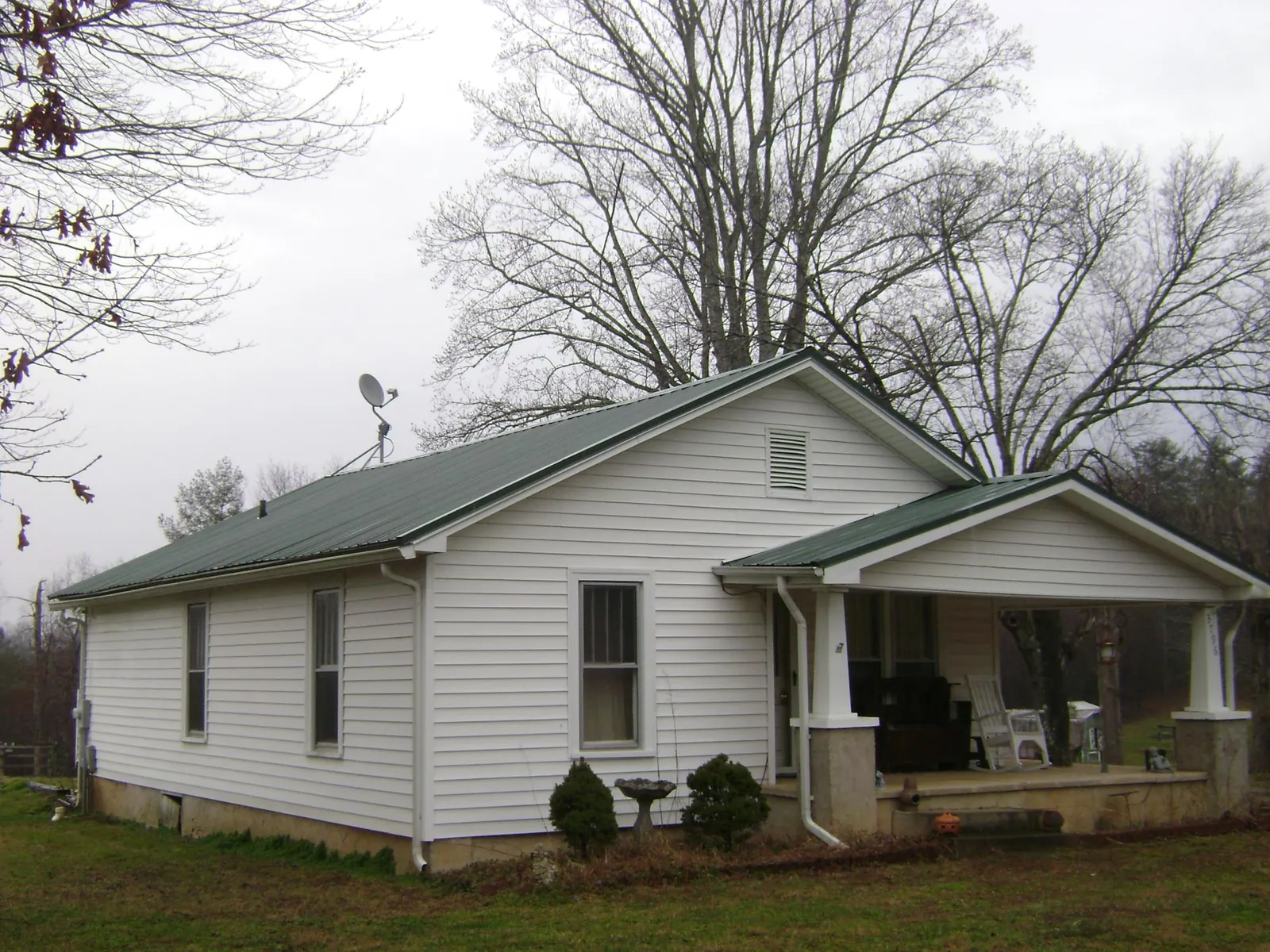Green metal roof on a white bungalow with a side porch in West Chester
