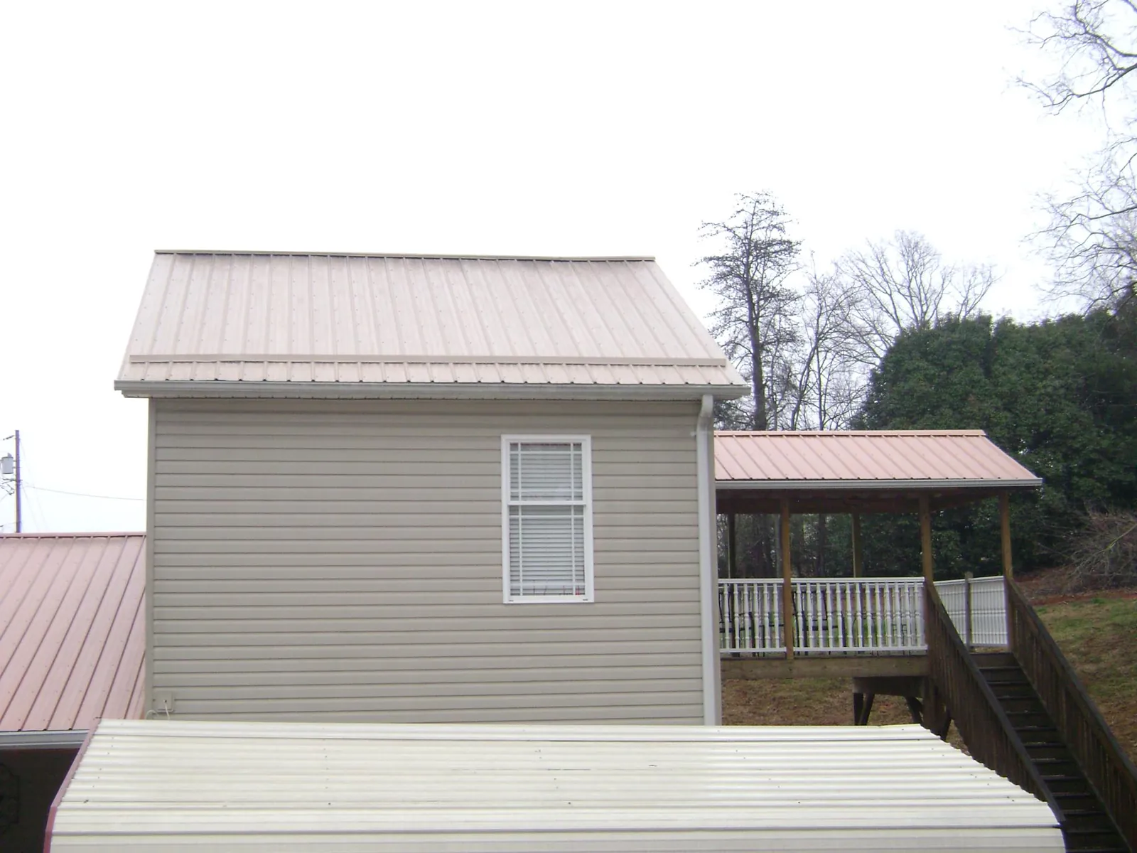 Tan metal roofs on a two story addition and attached porch, from a Roof Replacement job in West Chester