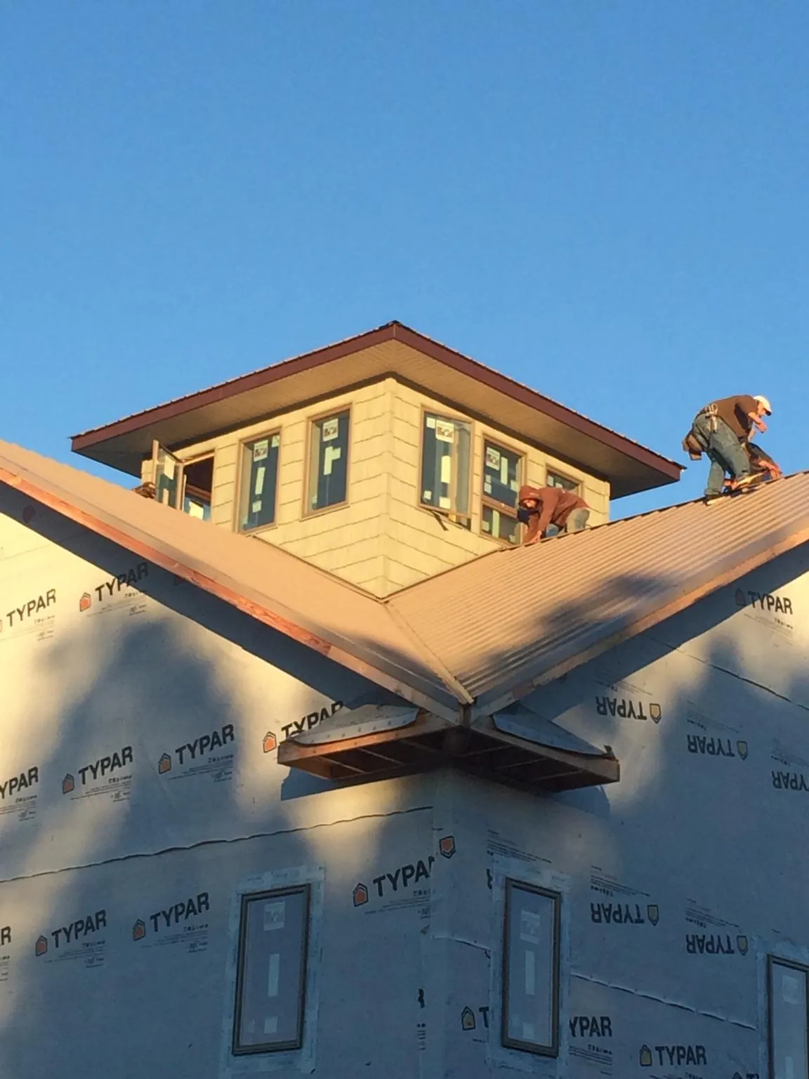Roofers working around a rooftop cupola on a new metal roof at sunset — Roof Waterproofing in West Chester by Roofing Brothers